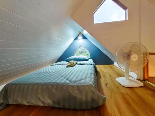 a bedroom with a bed and a fan in a attic at Baan Klangkao - บ้านกลางเขา สะปัน in Ban Huai Ti