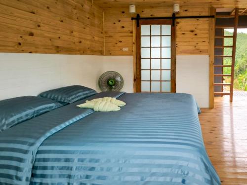 a blue bed in a room with wooden walls at Baan Klangkao - บ้านกลางเขา สะปัน in Ban Huai Ti