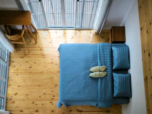 a blue couch with two pillows on a wooden floor at Baan Klangkao - บ้านกลางเขา สะปัน in Ban Huai Ti