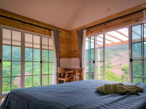a bedroom with a bed and large windows at Baan Klangkao - บ้านกลางเขา สะปัน in Ban Huai Ti