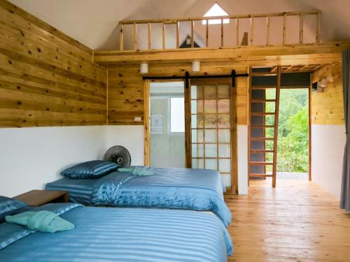 two beds in a room with wooden walls at Baan Klangkao - บ้านกลางเขา สะปัน in Ban Huai Ti