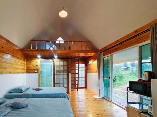 a bedroom with two beds and a balcony at Baan Klangkao - บ้านกลางเขา สะปัน in Ban Huai Ti