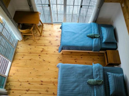 a room with two beds with blue sheets and a wooden floor at Baan Klangkao - บ้านกลางเขา สะปัน in Ban Huai Ti