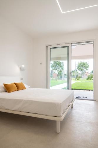 a white bedroom with a bed and a large window at Armonia Suites - Aria e Fuoco in Verona