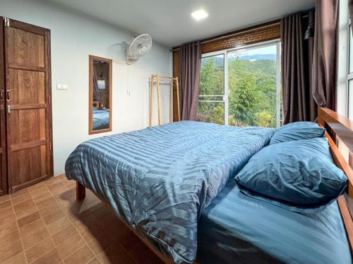 a bedroom with a large bed with a window at Baan Klangkao - บ้านกลางเขา สะปัน in Ban Huai Ti
