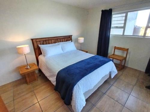 a bedroom with a bed and two lamps and a window at Ce-la-vie in Gqeberha
