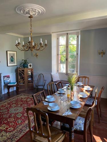 a dining room with a table with chairs and a chandelier at Maison de Haouret in Libaros