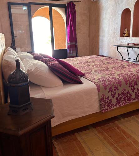 a bedroom with a bed with a table and a window at Riad Dar Bergui in Ouarzazate