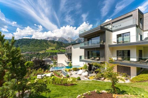 an exterior view of a house with mountains in the background at Boutique Aparthotel Chalets Coburg in Schladming