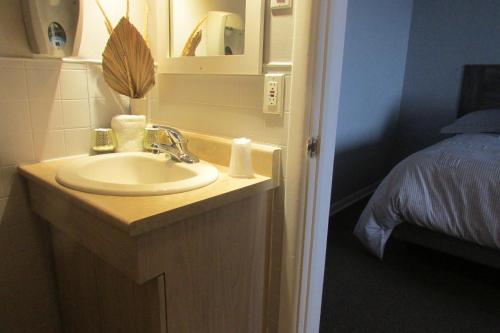 a bathroom with a sink and a bed at Motel Restaurant Nanook in Cap-Chat