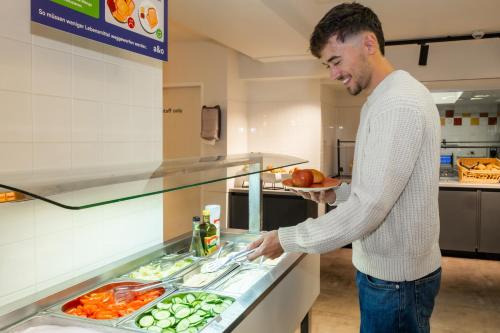 a man standing in front of a food counter at a&o Berlin Friedrichshain in Berlin