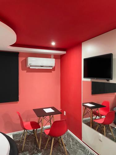 a room with red walls and tables and a flat screen tv at Agha Motel in Canela