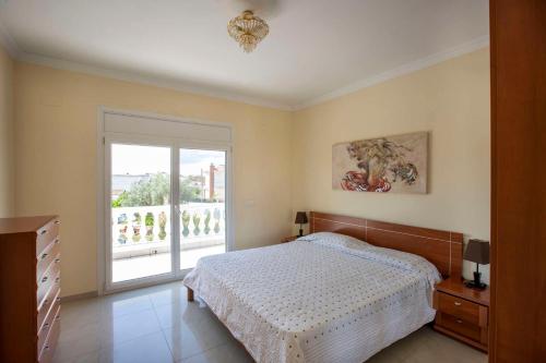 Un dormitorio con una cama y una puerta corrediza de vidrio. en Villa CARMENÇÓ, en Castelló d'Empúries