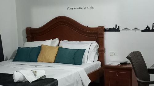 a bed with a wooden headboard and pillows on it at Hotel Neiva Providencia in Neiva