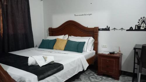 a bedroom with a bed with white sheets and colorful pillows at Hotel Neiva Providencia in Neiva