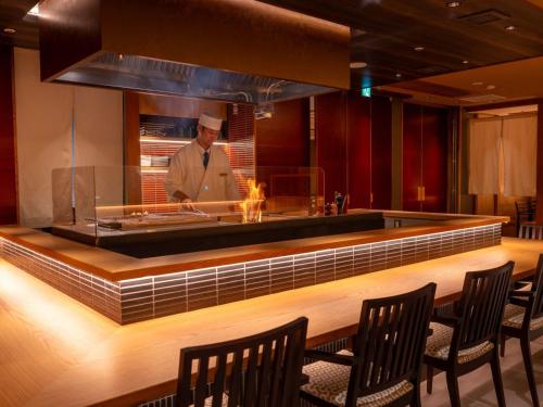 a chef standing behind a counter in a restaurant at APA Hotel Sendai Eki Itsutsubashi in Sendai