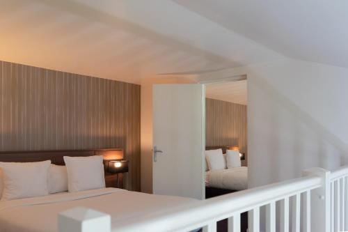 a bedroom with two beds and a mirror at Paxton Paris MLV in Ferrières-en-Brie