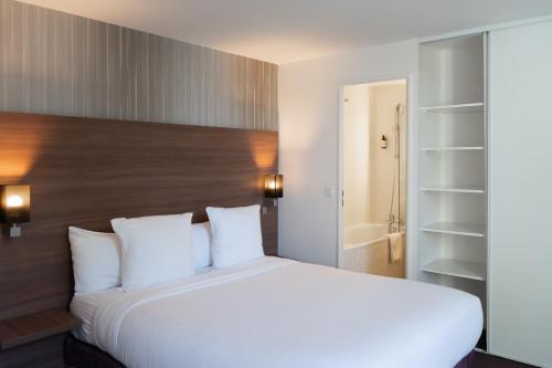 a bedroom with a large white bed and a bathroom at Paxton Paris MLV in Ferrières-en-Brie