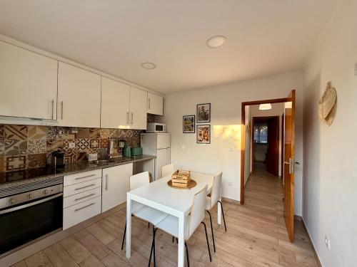 a kitchen with white cabinets and a white table and chairs at Casa das Laranjeiras in Alfarim