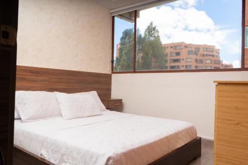 a bedroom with a bed and a large window at Hotel Santiago de Compostella Suites in Cuenca