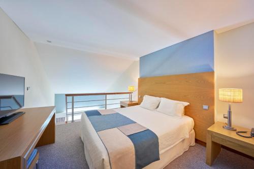 a bedroom with a bed and a desk and a television at Hotel Do Caracol in Angra do Heroísmo