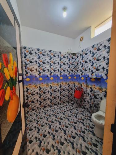 a bathroom with a toilet and a wall of rocks at Marari Sophy Villa in Mararikulam
