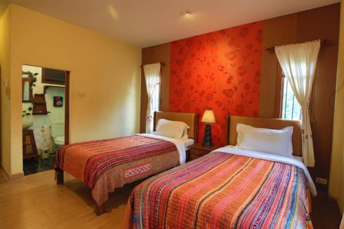 a hotel room with two beds and a mirror at Plumeriahome near Chiangmai Airport in Chiang Mai