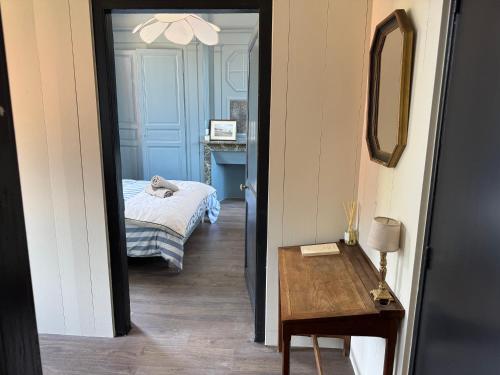a room with a bed and a table and a mirror at Maison Eudoise, piscine et spa in Eu