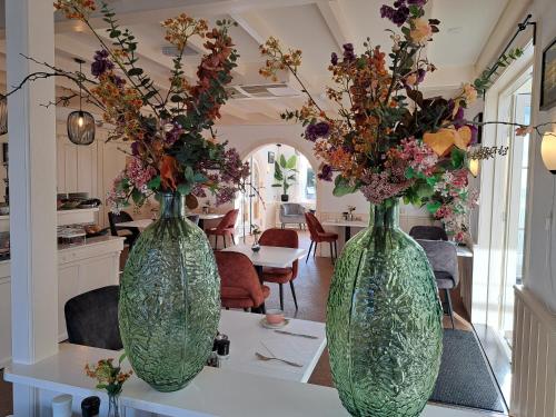 two green glass vases with flowers on a table at Hotel Het Gouden Boltje in De Koog