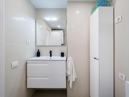 un bagno bianco con lavandino e specchio di Apartamento Primera línea playa a Las Palmas de Gran Canaria