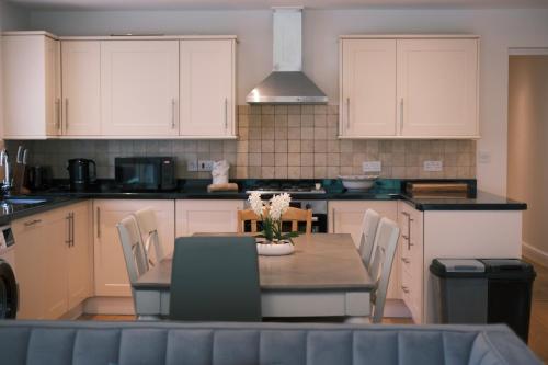 a kitchen with a table and chairs and white cabinets at Oxford Nest - Spacious & Luxury Apartments in Oxford