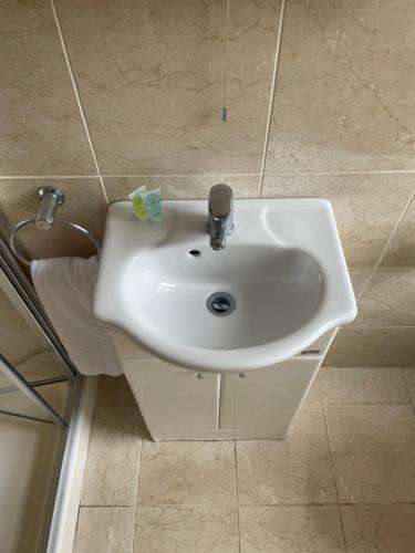 a white sink in a bathroom with tile walls at Crawford House- ScholarLee Living Apartments in Cork
