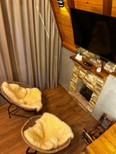 a living room with two chairs and a fireplace at Chalé Sossego da Mata in São José dos Pinhais