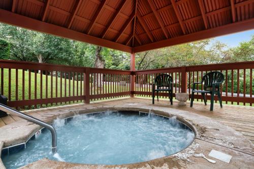 a hot tub on a deck with two chairs at Mountain Meadows in Pigeon Forge