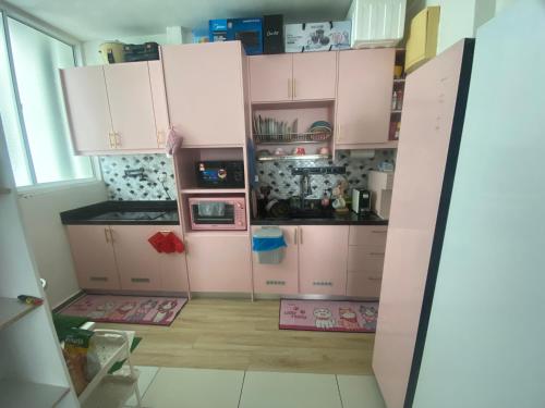 a small kitchen with pink cabinets in a room at Palmera Residensi in Kajang