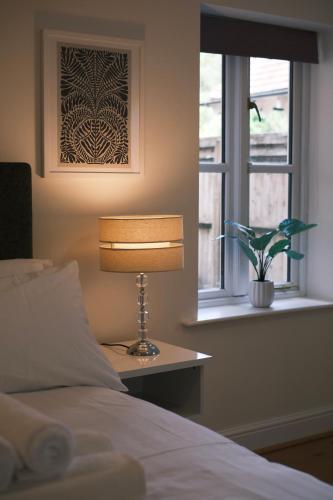 a bedroom with a bed and a lamp and a window at Oxford Nest - Spacious & Luxury Apartments in Oxford