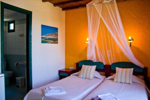 2 łóżka w pokoju z pomarańczowymi ścianami w obiekcie Archipelagos w mieście Naksos
