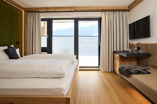 a bedroom with two beds and a large window at Hotel Rosenstock - Erwachsenenhotel - Adults only 15 plus in Fischen