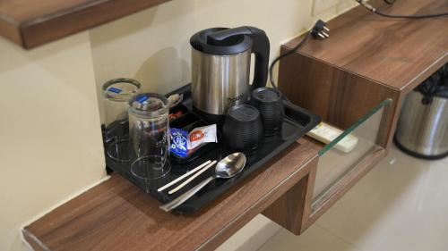 a coffee maker and utensils on a kitchen counter at Hotel Prime Suites - Baner in Pune