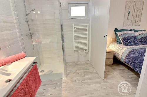 a bathroom with a walk in shower next to a bed at Le brulis in Ville Hermel