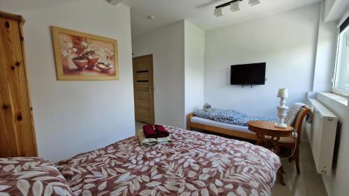 a bedroom with a bed and a tv on the wall at Bos-Znam Pokoje in Gdynia