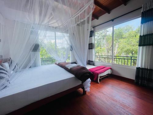 a bedroom with a bed and a large window at Ella Serene Stay in Ella