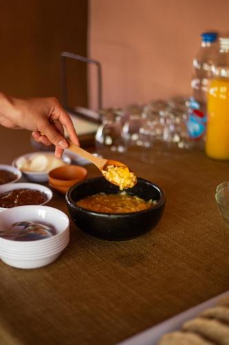 a person spooning food into a pan on a table at DON JUAN posada andina in Tilcara