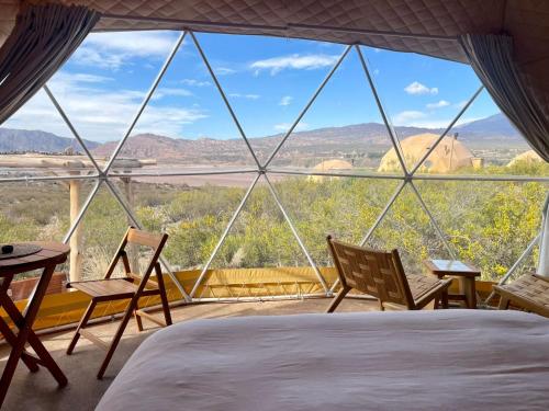 a bedroom with a bed and chairs and a view at El Nido Domos in Mendoza