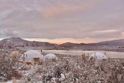 a snow covered field with two domes in front of a lake at El Nido Domos in Mendoza