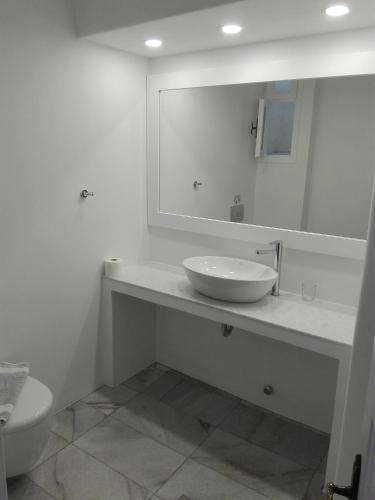a white bathroom with a sink and a mirror at Villa Irini in Naousa