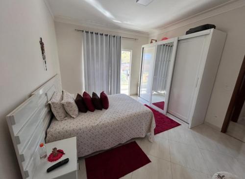 a bedroom with a bed with red pillows on it at Casa Alto Padrao in Pouso Alegre