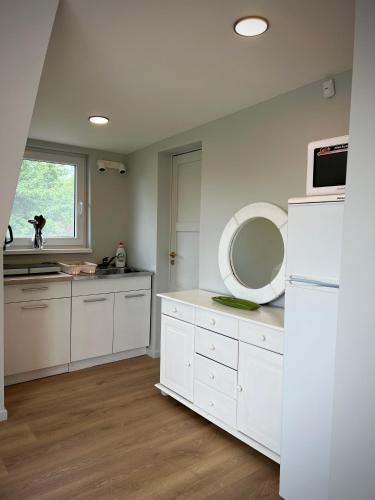 a white kitchen with a sink and a mirror at Lejnieki Apartment 4 in Pape