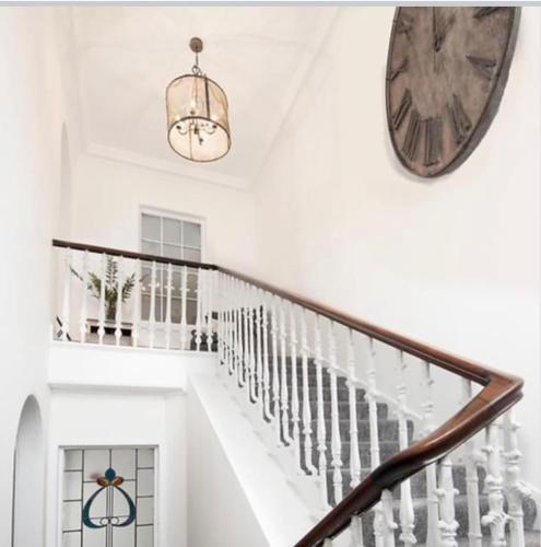 a white staircase with a clock on the wall at Stylish Town Apt in Hawick