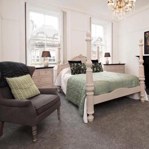 a bedroom with a bed and a chair and a chandelier at Stylish Town Apt in Hawick